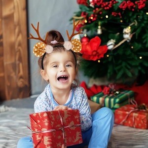Close-up of reindeer antler headband with plush balls and brown ears worn by a child