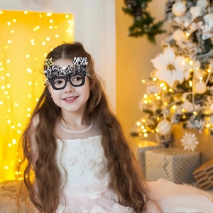 Kind trägt Silvesterbrille 2024 mit Glitzersternen und Krone als Partydekoration