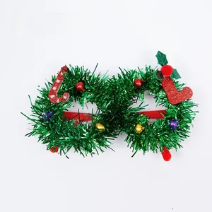 Close-up of Christmas party glasses with green tinsel, red candy cane and bells decor