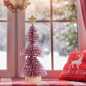 Close-up of pink mini Christmas tree with white snow flocking and gold star topper