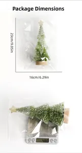 Miniature snow-dusted pine Christmas tree with gold star topper and wood base in packaging