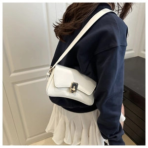 Close-up of minimalist white leather crossbody bag with elegant gold-tone metal buckle