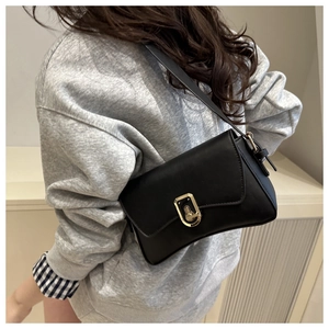 Detail shot of black leather handbag featuring a sleek golden metal clasp and adjustable strap