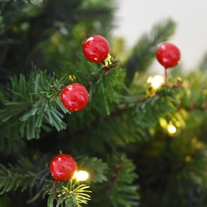 Close-up of artificial red Christmas berries with festive LED lights and green pine needles