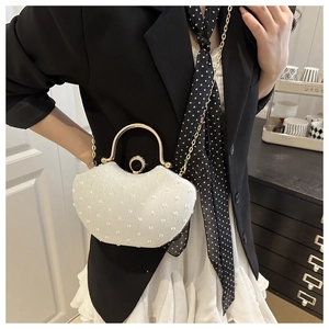 Detail of white semi-circle evening bag featuring pearl decor and gold handle