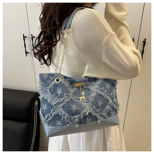 Detail of star-patterned denim tote bag featuring fringe edges and a gold deer charm