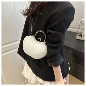 Detail of white evening bag with pearl-like texture and golden metal ring handle