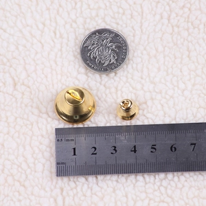 Macro detail of polished gold Christmas bells in two sizes on white plush fabric background