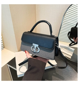 Detail of silver CD-style buckle on grey textured fabric and black leather flap bag