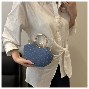 Detail of blue denim saddle bag with white jacquard pattern and gold metal handle