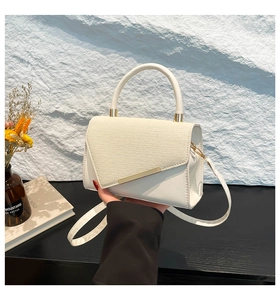 Détail du sac à main en cuir blanc et paille avec rabat géométrique et finitions dorées