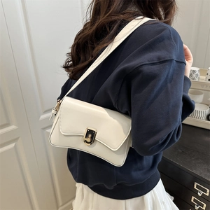 White minimalist leather underarm bag with a unique black and gold clasp shown on model