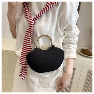 Detail of black saddle bag with textured embroidery and gold metal hardware handle