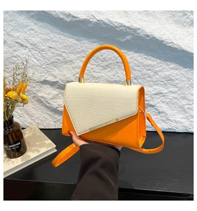 Détail du sac à main orange et beige avec texture tissée et barre métallique dorée