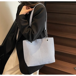 Macro view of light purple textured tote bag with silver chain strap on a staircase