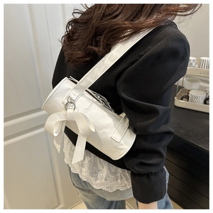 Detailed view of a white cylindrical shoulder bag with a large decorative bow on the side