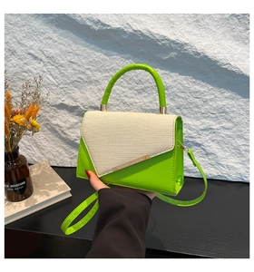 Détail d'un sac vert en similicuir avec rabat en paille et ornements métalliques dorés