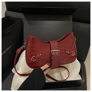 Close-up of red crocodile embossed baguette bag with silver buckles in a gift box set
