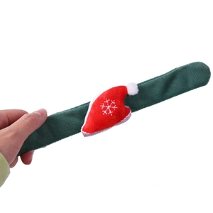 Close-up of a plush green Christmas slap bracelet featuring a mini red Santa hat with snowflake