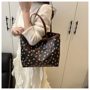 Détail d'un cabas noir à imprimé cerises avec des anses marron porté par un mannequin