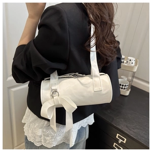 Detail of white cylindrical shoulder bag with elegant ribbon bow and smooth PU leather