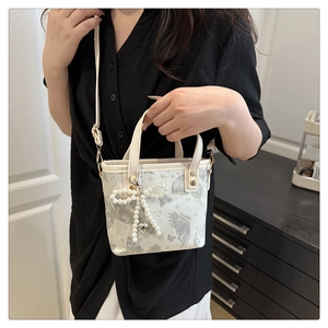 Dettaglio della mini borsa a secchiello con fiocco di perle e ciondolo a cuore