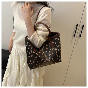 Vue détaillée du sac cabas avec imprimé cerises rouges et anses en cuir marron foncé