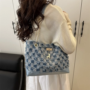 Denim checkerboard tote bag with gold chain strap and deer charm on female model