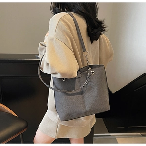 Detail of grey textured tote bag with silver chain strap shown in a modern urban setting