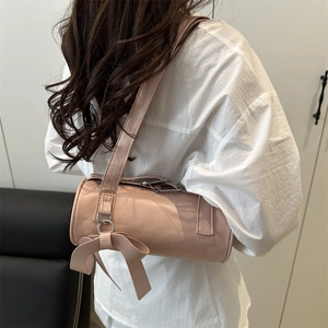 Pink cylinder shoulder bag with large bow detail shown on model from side-rear view