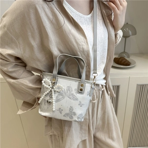 Elegante borsa a secchiello con ricamo a farfalla e fiocco di perle sulla modella