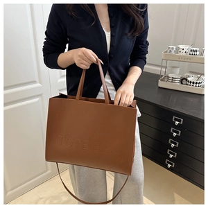 Detail of caramel leather tote bag with embossed logo and versatile shoulder straps