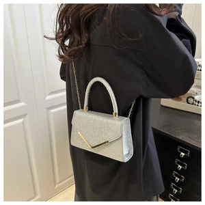 Silver sequin mini bag with gold chain strap shown on model in a minimalist setting