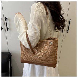 Detail of dark brown straw tote with herringbone weave, leather strap, and deer pendant