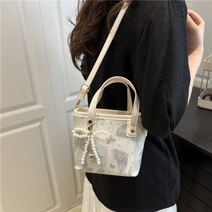 Elegante borsa a secchiello avorio con stampe farfalle viola e ciondolo perla sul modello
