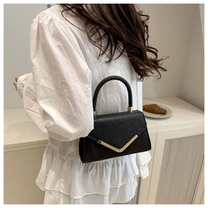 Close-up of black glitter handbag with gold V-hardware and metallic chain strap