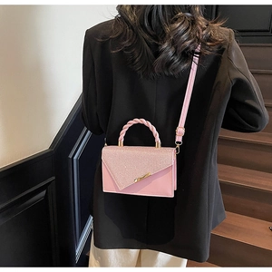 Vue détaillée du sac rose clair avec rabat scintillant et poignée torsadée texturée