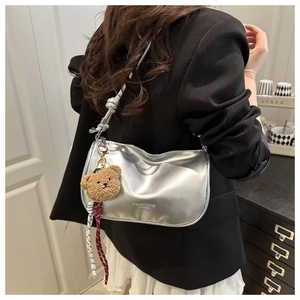 Silver metallic pillow bag with adjustable strap and cute brown plush bear charm detail