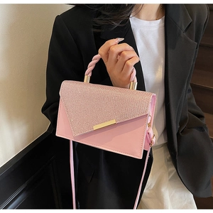 Détail du sac à paillettes rose avec poignée en spirale et barre dorée sur veste