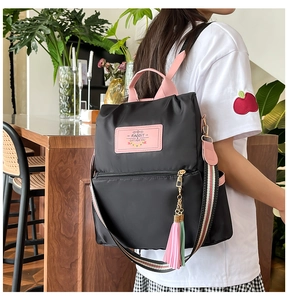 Close-up of black nylon backpack with pink handles and colorful striped shoulder straps