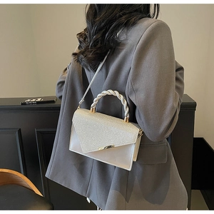 Détail du sac bandoulière argenté avec rabat en V pailleté et poignée torsadée en métal