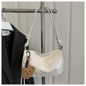 Detail of white semi-circular shoulder bag with bear charm and knotted straps