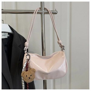 Detail of pink leather pillow bag with brown plush bear charm and knotted shoulder strap