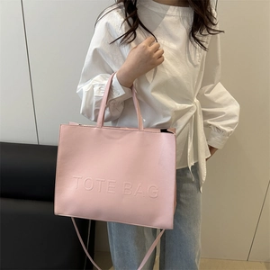 Pink minimalist leather tote bag with embossed text and adjustable shoulder strap