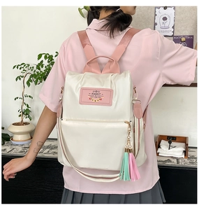 Close-up of cream and pink nylon backpack with adjustable straps and striped shoulder belt