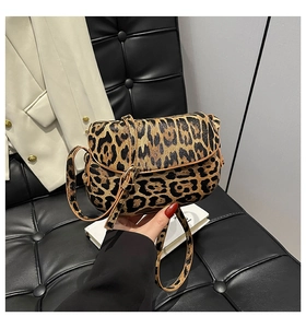 Detailed view of leopard print crossbody bag with brown trim and adjustable strap