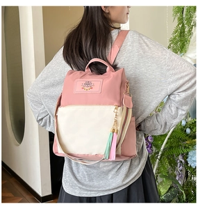 Detail of pink nylon backpack with Rabbit Gift patch, tassel charm and striped straps