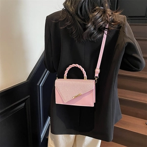 Sac à main rose chic avec rabat en V scintillant et poignée tissée porté par un mannequin