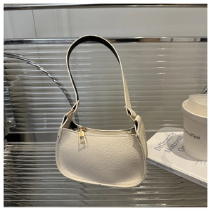 Close-up of cream pebble grain leather texture and gold hardware on baguette bag