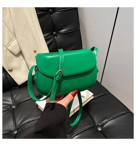 Detail of a bright green faux leather saddle bag with smooth finish and adjustable strap